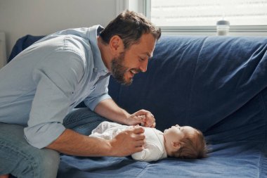 Gururlu beyaz bir baba yeni doğmuş bir kızla konuşuyor. Gülümseyen mutlu bir ebeveyn ve kız çocuğu. Otantik yaşam tarzı mutlu ebeveynlik anı. Bekar baba aile hayatı..