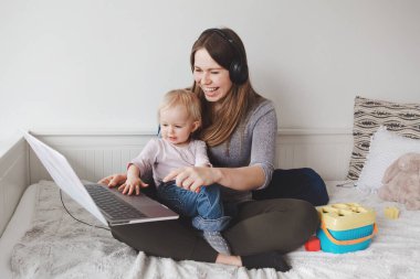 Evde dizüstü bilgisayarla çalışan bebekle genç beyaz anne blogcusu. Çocuk yürümeye başlayan serbest kadın öğrencilerin çalıştığı yer. Evde kalıp bekâr bir anne olarak online işten para kazanacağım..