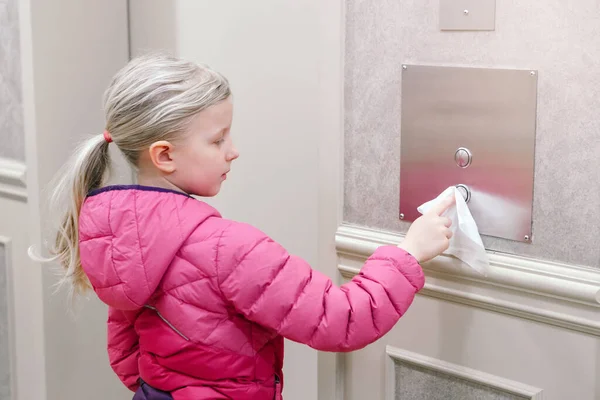 Caucasian girl pushing elevator button with disinfecting wet wipe. Precaution against virus spread. COVID-19 coronavirus danger and fast epidemic virus contagion concept.