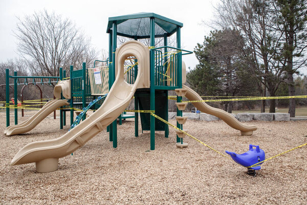 Торонто, Онтарио, Канада - 26 марта 2020 года: открытая игровая площадка Ced. Детская игровая площадка закрыта желтой лентой, чтобы остановить скопление людей. Карантин коронавируса
.