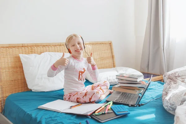 白人の女の子の子供がベッドに座って ラップトップインターネット上でオンラインで学ぶ 自宅での隔離中にビデオチャット上の仮想クラスレッスン学校 遠隔ビデオ教育クラス — ストック写真