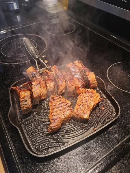 フライパンで焼いたステーキ 焼きたてのおいしいジューシーなローフ肉をキッチンのオーブンで煙で焼きます 本物の家庭料理 — ストック写真