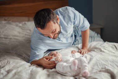 Gururlu beyaz bir baba yeni doğmuş bir bebekle oynuyor. Gülümseyen bir ebeveyn, çocuk kızıyla konuşuyor. Otantik yaşam tarzı mutlu ebeveynlik anı. Bekar baba aile hayatı..