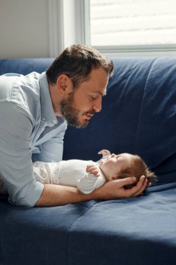 Gururlu beyaz bir baba yeni doğmuş bir kızla konuşuyor. Gülümseyen mutlu bir ebeveyn kızı sakinleştiriyor. Otantik yaşam tarzı mutlu ebeveynlik anı. Bekar baba aile hayatı..