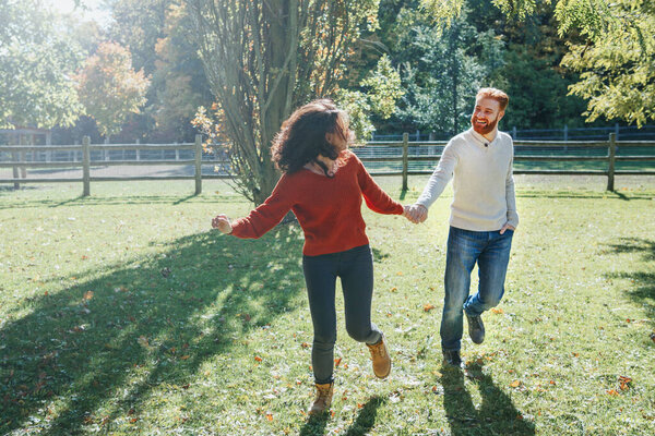 Happy couple man and woman in love walking in park outdoor. Lovely beautiful Caucasian heterosexual people dating walking on autumn fall summer day. Adult people holding hands.