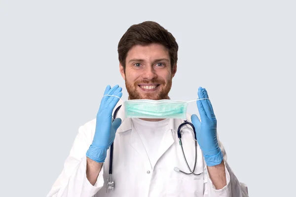 Muž doktor staví na lékařské masky izolované. — Stock fotografie