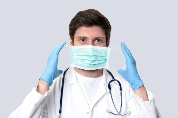 Man Doctor Puts på medicinsk mask isolerad. — Stockfoto