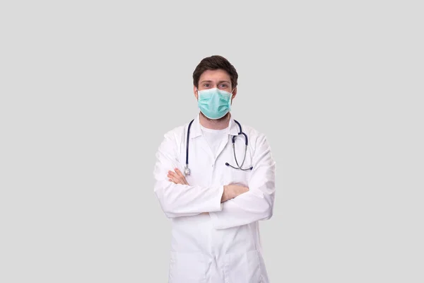 Doctor dragen van medische masker handen gekruist geïsoleerd. — Stockfoto