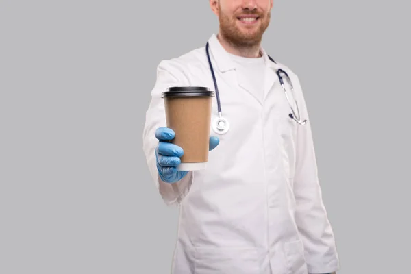 Doctor Showing Coffe To go Cup viselése kesztyű és mosolygós izolált. Kávé Vidd el a kupát — Stock Fotó