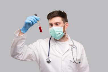 Erkek Doktor, üzerinde tıbbi maske ve eldiven olan kan analizini inceliyor. Portre. Virüs Analizi Konsepti