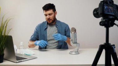 Erkek Blogger Streaming, Tıbbi Maske Giyen Eldiven Giyiyor. Video İçerik Yapıcı. Virüs kavramı videosu. Blogger Tıbbi Maske Kullanımı.