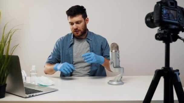 Αρσενικό Blogger Streaming βάζει στην ιατρική μάσκα φορώντας γάντια. Δημιουργός περιεχομένου βίντεο. Βίντεο Ιού Concept. Χρήση ιατρικής μάσκας blogger. — Αρχείο Βίντεο
