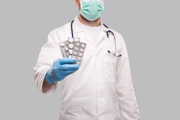Man Doctor visar piller bär medicinsk mask. Läkare som håller i tabletter. Corona Virus Concept. Piller på nära håll. Fokus på tabletter — Stockfoto