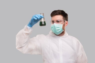 Kimyasal Takım Elbiseli Erkek Laboratuvar İşçisi, Tıbbi Maske Giyiyor ve Renkli Sıvı ile Gözlük Takıyor. Bilim, Tıp, Virüs Konsepti. Doktor.