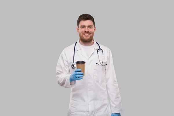 手袋を着用し 独立した笑みを浮かべてカップに行くためにコーヒーを示す医師 医学的概念 — ストック写真