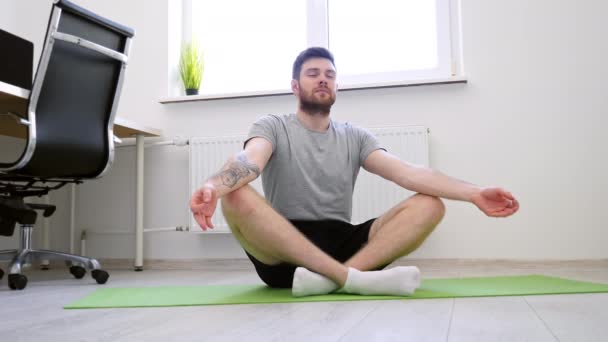Egy férfi jógázik otthon. Lótuszpóz. Home Sport, Egészséges élet, Karantén koncepció — Stock videók