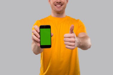 Telefonu tutan adam başparmağını kaldırıyor. Eve Teslimat. Sipariş Çevrimiçi Teknoloji. Yeşil Ekran Kapat 'ı ara. İzole edilmiş