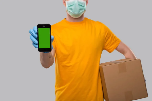 Homem Entrega Vestindo Máscara Médica Luvas Mostrando Telefone Segurando Caixa — Fotografia de Stock