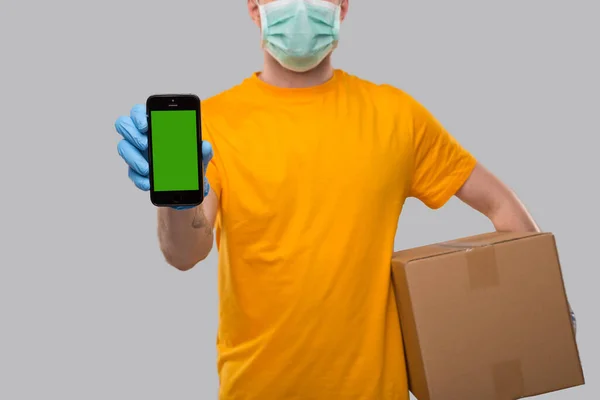 Levering Mand Iført Medicinsk Maske Handsker Viser Telefon Holding Box - Stock-foto