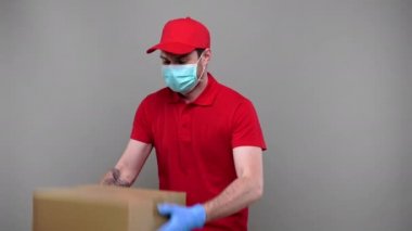 Teslimatçı, tıbbi maske takıyor ve karton kutuyla oynuyor ve müşteriye veriyor. Teslimatçı Çocuk Eve Teslim Paketi.