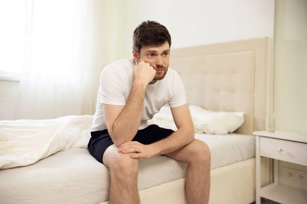 Ο άντρας που κάθεται στο κρεβάτι κουρασμένος. Απογοητευμένος άντρας στο σπίτι. Μοναχικός Βαρετός στο κρεβάτι. — Φωτογραφία Αρχείου
