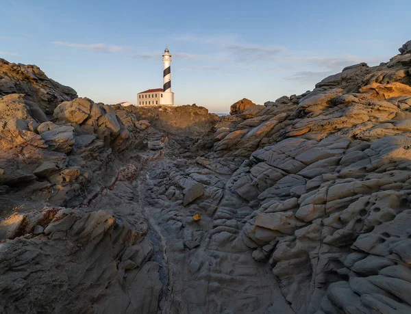 Şafakta Menorca 'nın kayalık bölgesinde siyah beyaz deniz feneri