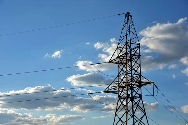 Bulutlu mavi gökyüzüne karşı yüksek voltajlı güç hattı