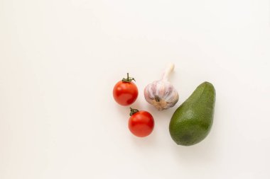 Beyaz bir zemin üzerinde izole edilmiş sarımsak ve avokado ile taze kırmızı kiraz domatesleri.