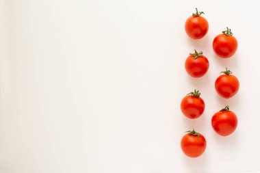 Çiftlikten taze kırmızı domatesler dikey bir çizgide beyaz bir arkaplanda ve bir kopyacı boşluğunda izole bir şekilde duruyor.
