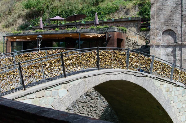 The old arched stone bridge is hung with many golden castles. A large number of locks on the bridge fence