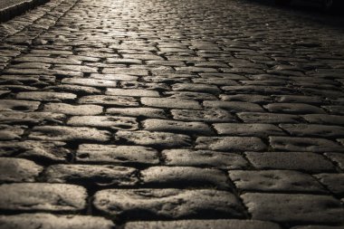 Siyah Arnavut kaldırımlı yolda gördüm ışık yansıması ile taş yol arka plan. Siyah veya koyu gri taş döşeme doku.
