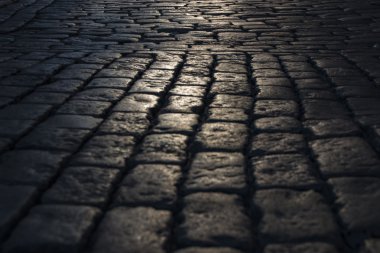 Siyah Arnavut kaldırımlı yolda gördüm ışık yansıması ile taş yol arka plan. Siyah veya koyu gri taş döşeme doku.