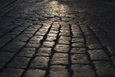 Siyah Arnavut kaldırımlı yolda gördüm ışık yansıması ile taş yol arka plan. Siyah veya koyu gri taş döşeme doku.