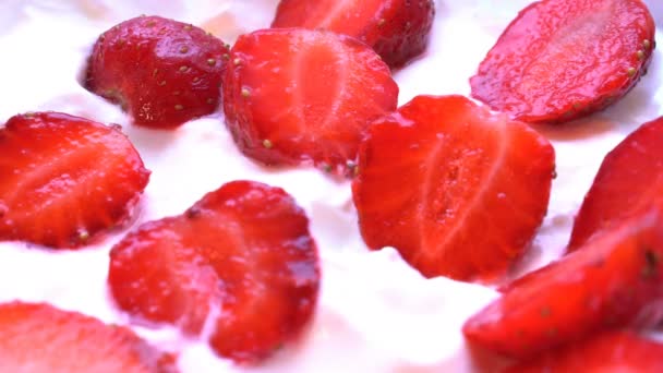 Des morceaux de fraise sont prélevés dans la crème à la cuillère. Macro shot . — Video