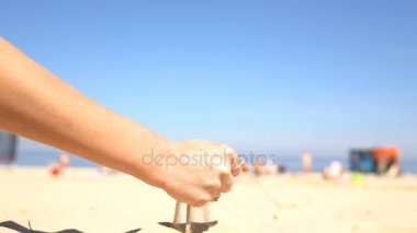 Sahilde bir kadının elinden dökülen kum.