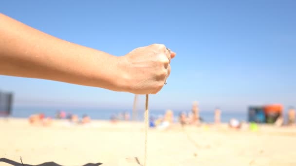 Zand gieten uit de handen van een vrouw op het strand. — Stockvideo