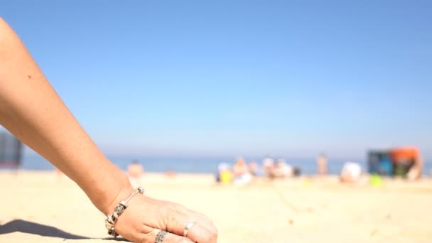 Zand gieten uit de handen van een vrouw op het strand. — Stockvideo