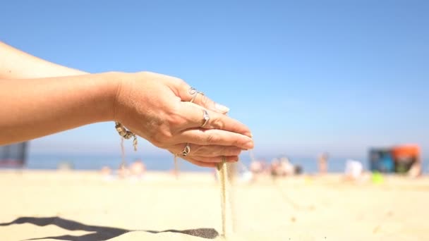 Areia derramando das mãos de uma mulher na praia . — Vídeo de Stock