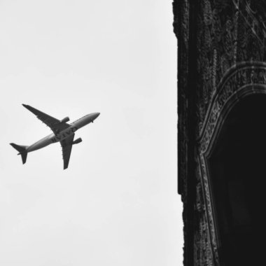 Delhi 'deki Kutub Minar yakınlarında, bulutlu gökyüzünde uçan uçak, gökyüzünde yüksek uçan uçak...