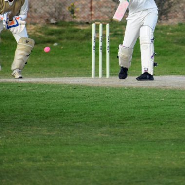 Güneşli bir günde sahada oynayan kriket oyuncusu, sahada oynayan kriket oyuncusu, sahada kriket oynayan oyuncular.