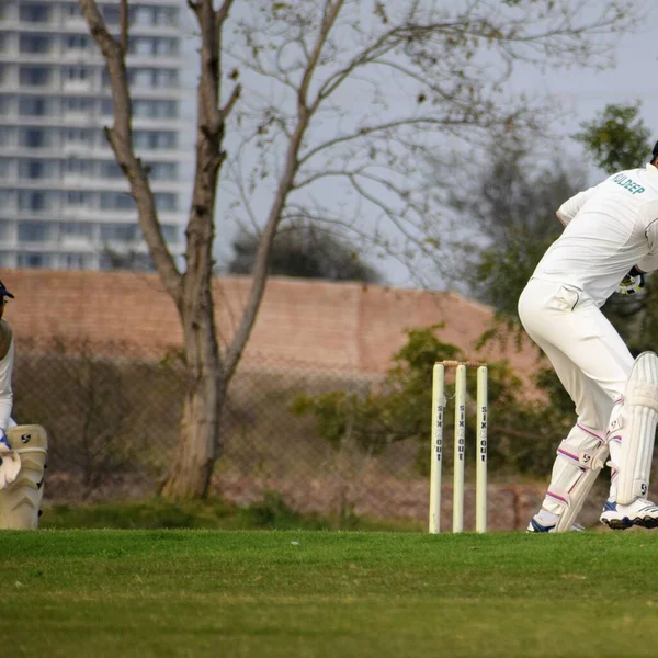 Full length of cricketer playing on field during sunny day, Cricketer on the field in action, Players playing cricket match at field