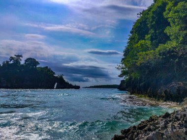 Gün batımında Crystal Körfezi 'nin manzaralı okyanus koyunda. Çarpışan dalgalar, demirlemiş tekneler, renkli günbatımı, Endonezya 'nın Bali kentinin güneydoğusundaki bir ada olan Nusa Penida' nın batı kıyısında bulunan tropikal titreşimler.