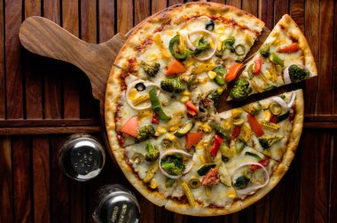 Biberli pizza tahtada, lezzetli ve çıtır vejetaryen pizzanın üst görüntüsü açık kahverengi masa arkasında Margherita.