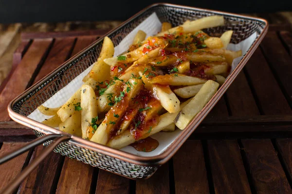 Tahtada patates kızartması, ahşap masa arkasında ev yapımı peynirli burger ve ahşap arka planda taze patates kızartması.