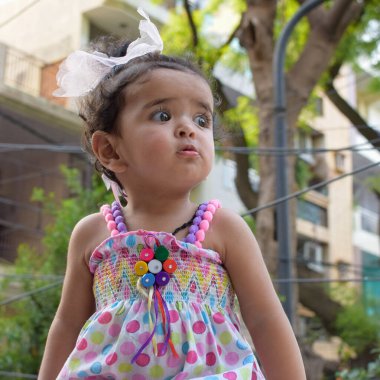 Çelenk takmış tatlı bir kız çocuğu resmi, 12 aylık sevimli gülümseyen bir kızın yakın plan portresi, küçük bebek, sevimli küçük bir kız bebek, gülümseyen ve açık hava fotoğraf çekimi için sevimli poz veren