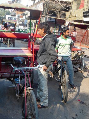 Delhi, Hindistan - 9 Aralık 2019: Chandni Chowk pazarında eski Delhi, Hindistan caddesinde, Rickshaw 'un sokak fotoğrafçılığı sıcağın altında aracı süren bisiklet rickshaw