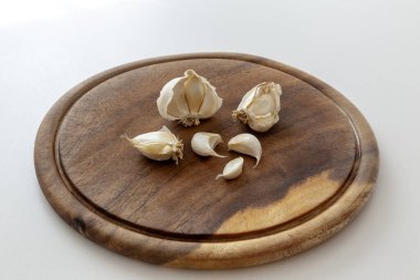 Tahta kesme tahtasının üzerinde taze sarımsak parçaları.