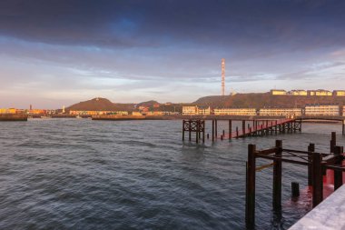 Heligoland - Rıhtımlı liman ve renkli evler gün doğumunda dramatik gökyüzü.