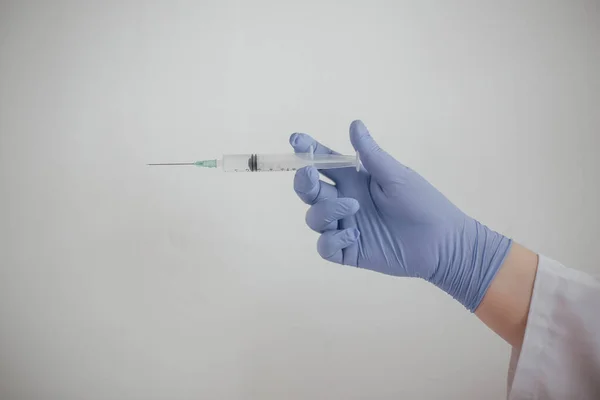 Doktor elinde koronovirüs aşısı olan bir şırınga tutuyor.