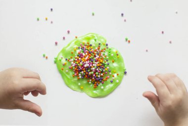 Çocuk elinde yeşil balçık oynuyor, şeffaf oyuncak. Küçük çocuk yeşil sümükle oynuyor.